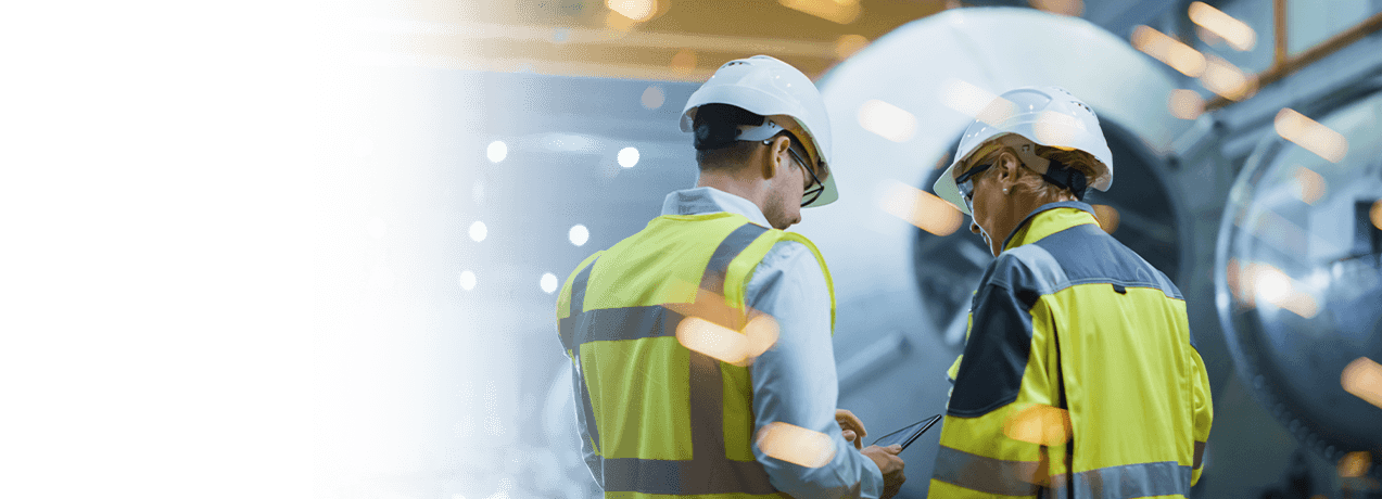 Specjaliści BHP w kaskach ochronnych analizują informacje na tablecie