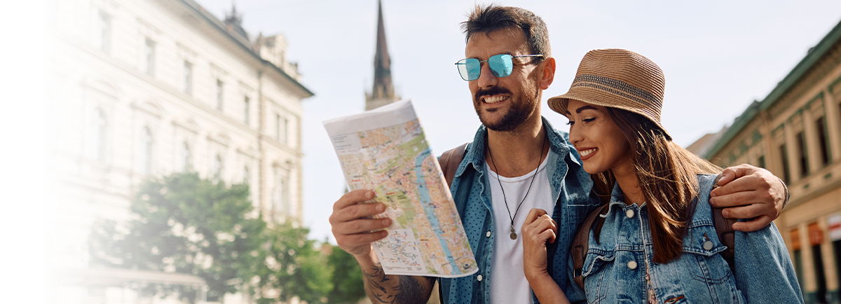 Dwójka turystów z mapą na tle zabytkowej architektury i wieży kościoła w centrum miasta