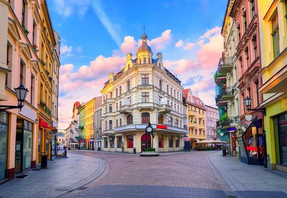 Malownicza, kolorowa ulica w Toruniu o zachodzie słońca z zabytkowymi kamienicami i latarniami. Idealne miejsce na spacer z karta EKUZ zapewniającą dostęp do opieki zdrowotnej podczas podróży po Europie.