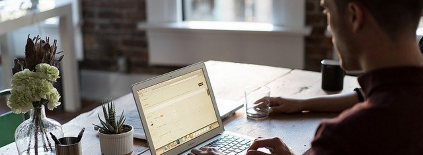 mężczyzna siedzący przy biurku z laptopem