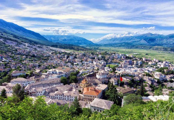 Panoramiczny widok na urokliwe miasto w Albanii, otoczone majestatycznymi górami, co przypomina o znaczeniu wykupienia ubezpieczenia turystycznego do Albanii przed podróżą.