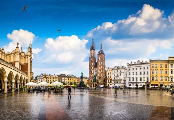 Widok historycznego Rynku Głównego w Krakowie, gdzie możesz uzyskać kartę EKUZ, na pierwszym planie charakterystyczna Bazylika Mariacka i Sukiennice.