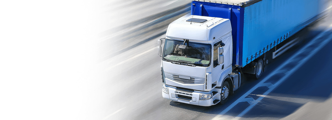 Niebiesko-biały samochód ciężarowy jadący autostradą jako symbol Ubezpieczenie OC przewoźnika drogowego i kolejowego w UNIQA