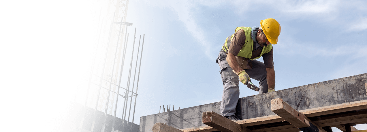 Mężczyzna w kasku i odzieży ochronnej pracujący na budowie