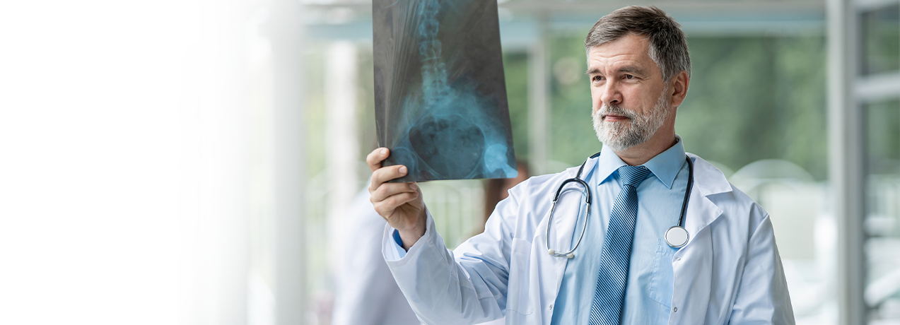 Lekarz w białym fartuchu i krawacie trzymający zdjęcie rentgenowskie