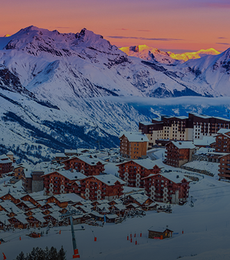 Panoramiczny widok na ośnieżoną górską wioskę o zachodzie słońca z kolorowym niebem i majestatycznymi szczytami w tle