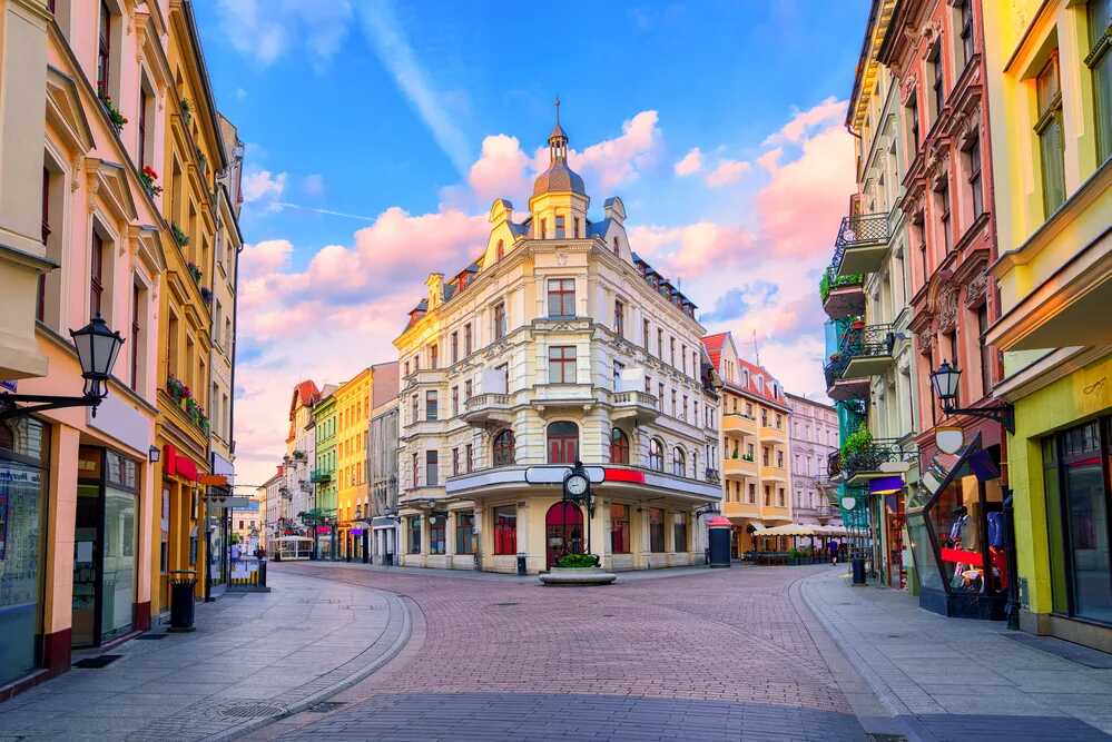 Malownicza, kolorowa ulica w Toruniu o zachodzie słońca z zabytkowymi kamienicami i latarniami. Idealne miejsce na spacer z karta EKUZ zapewniającą dostęp do opieki zdrowotnej podczas podróży po Europie.