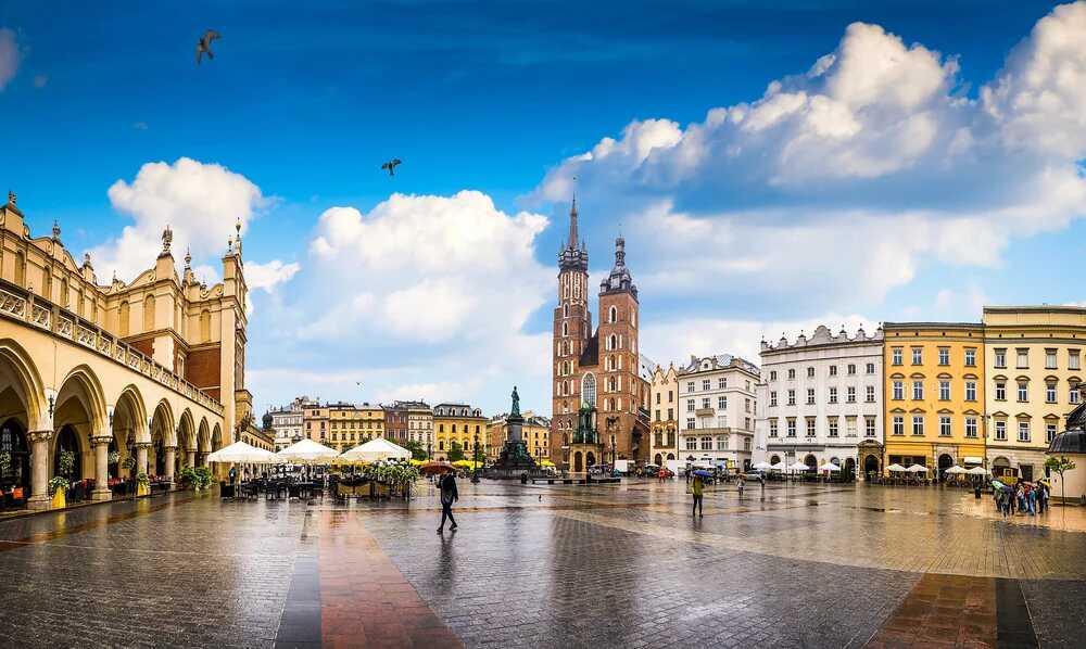 Widok historycznego Rynku Głównego w Krakowie, gdzie możesz uzyskać kartę EKUZ, na pierwszym planie charakterystyczna Bazylika Mariacka i Sukiennice.